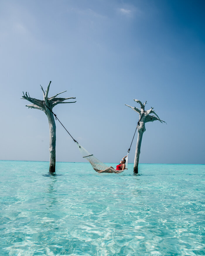 A hammock resting over calm tropical water at dusk